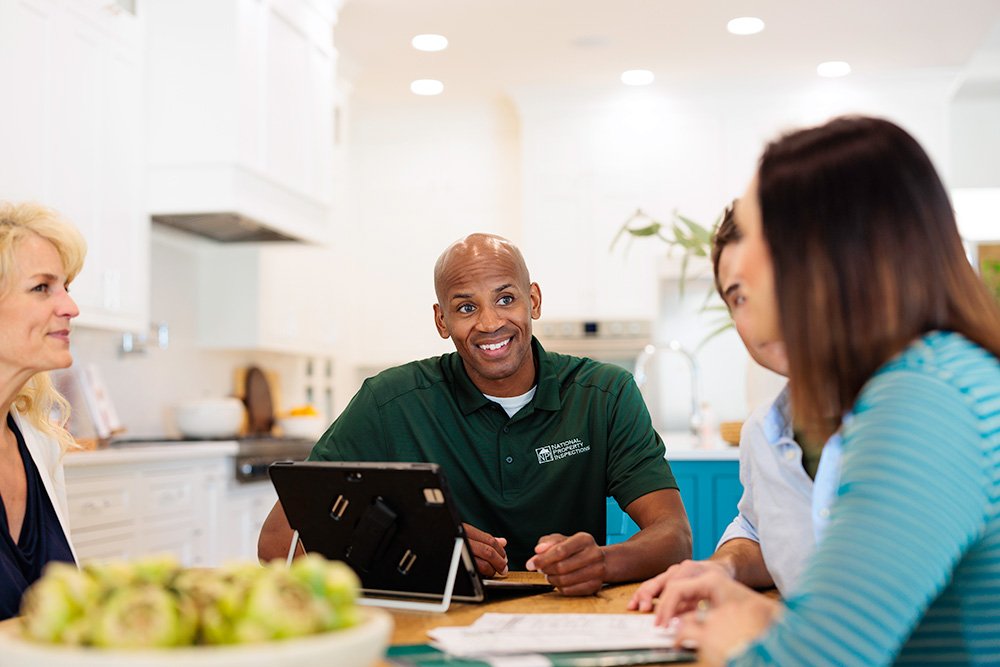 A man collaborates with two business professionals on a laptop in a casual IT consulting meeting.